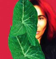 Woman in front of red background with green leaf in front of one eye