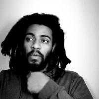 black and white image, handsome brown man with beard and long free-form dreads. 