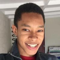 Boy smiling at camera wearing a denim jacket and red shirt.  