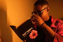 Man in glasses reading book while sipping from crystal glass